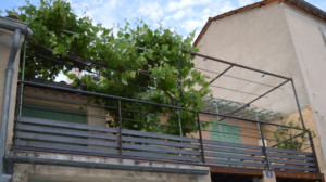 Création d'une terrasse en bois avec garde-corps et treille métallique sur mesure avec vigne façade orange avec volets vert Ferronnerie delbart les Mées 04190 alpes de haute Provence 04