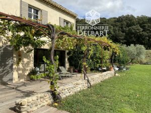 treille en fer forgé fixé contre une façade et terrasse entouré de vigne vierge gazon Ferronnerie Delbart Haute-Provence 04.