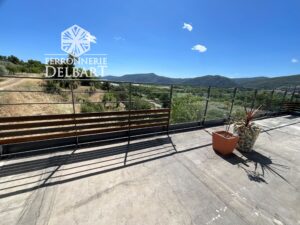 rampe en acier à lisse horizontale et partie verre positionner sur une terrasse béton 3 pots de plantes verte entouré dfe végétation. Ferronnerie Delbart les Mées en Haute-Provence 04.