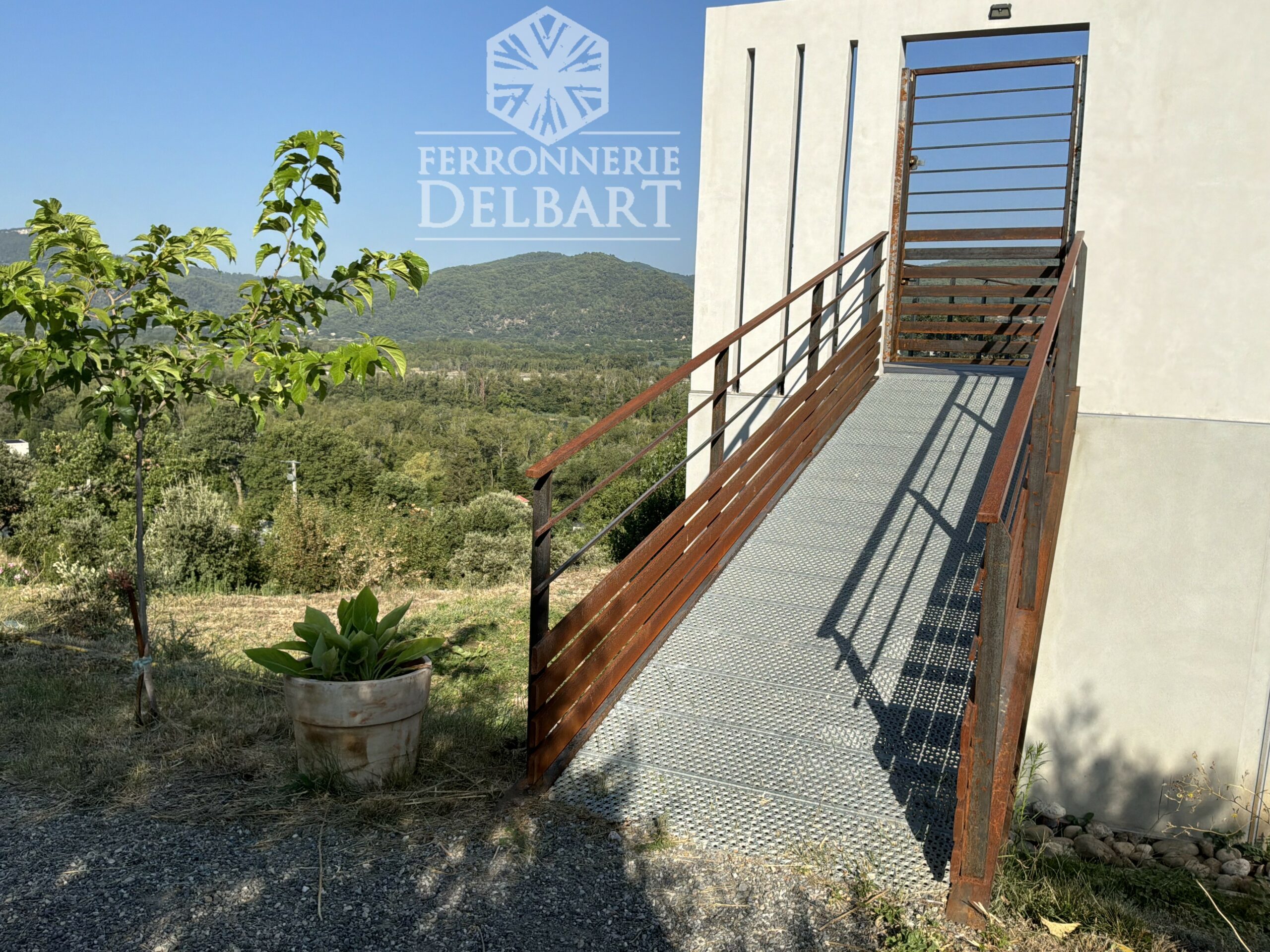 passerelle porte en acier entouré de végétation. Ferronnerie Delbart les Mées Haute-Provence.